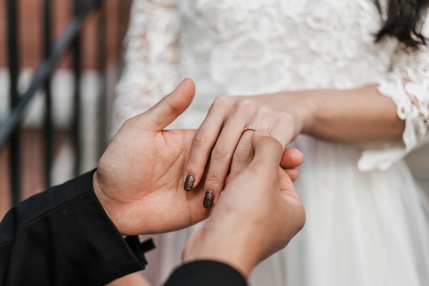 Free photo groom placing wedding ring on bride's finger