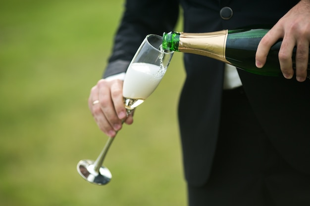 Groom pouring champagne in a flute