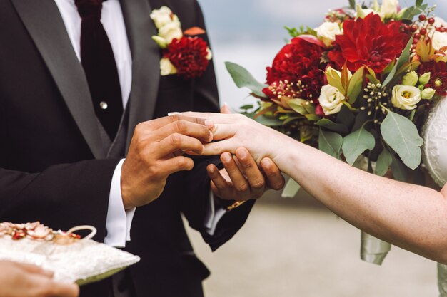 Жених надевает обручальное кольцо на палец невесты