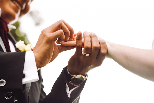 Бесплатное фото Жених надевает обручальное кольцо на палец невесты