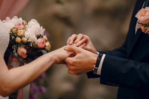 Free photo groom putting ring on bride's finger