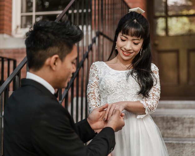 Groom putting wedding ring on bride's finger