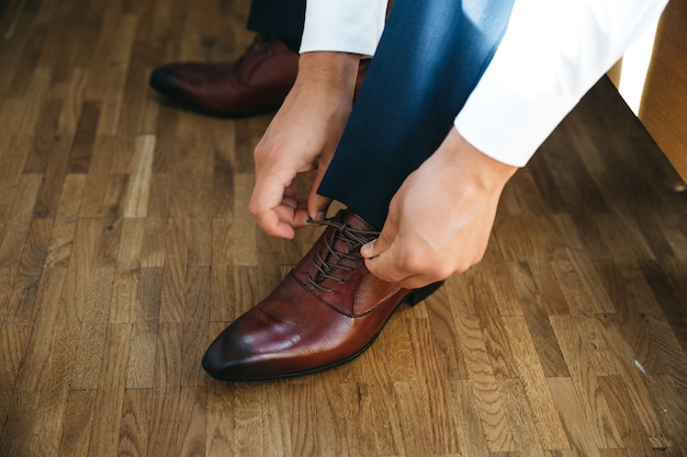 Free photo groom ties laces on his shoes