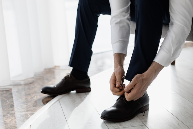 Free photo groom ties laces on his shoes