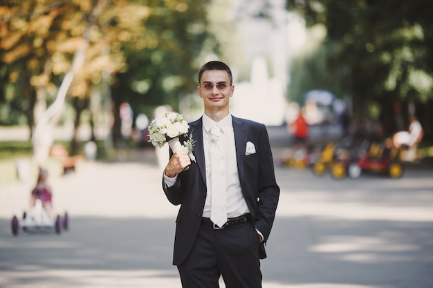 Groom with a bouquet in a park