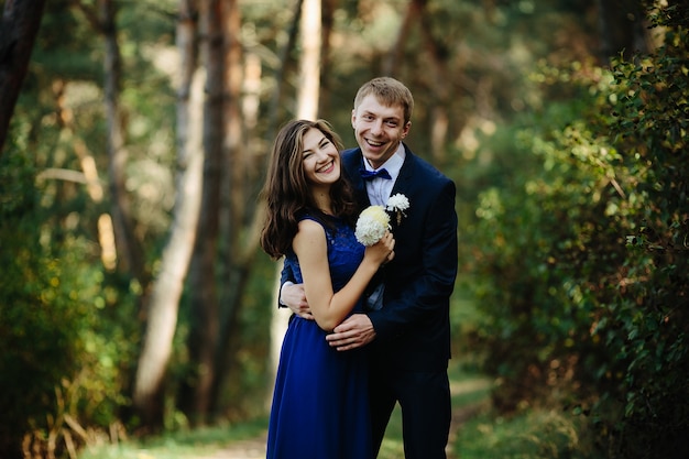 Groomsman hugging bridesmaid standing in forest