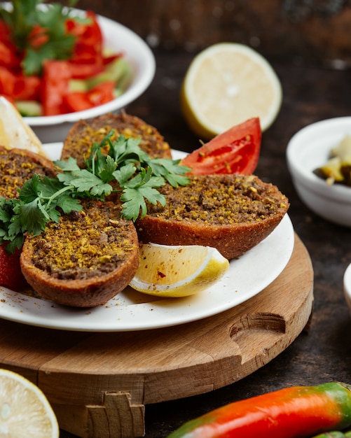 Ground meat in fried bread with slices of lemon and tomato