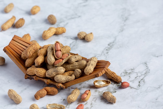 Groundnuts in wooden plate put on white marble floor