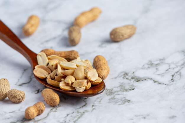 Groundnuts in wooden spoon put on white marble floor