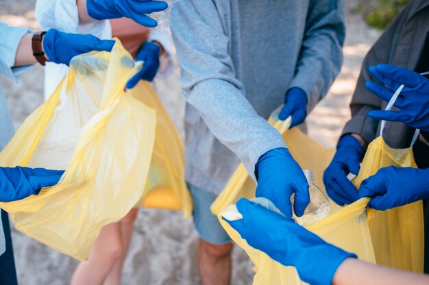 Группа активистов друзей собирает пластиковые отходы на пляже. Охрана окружающей среды.