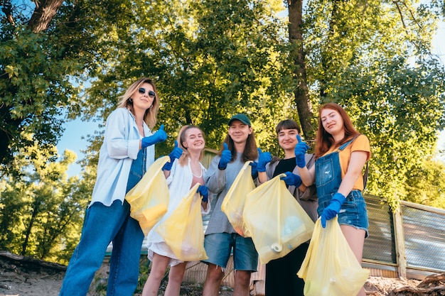 ビーチでプラスチック廃棄物を収集する活動家の友人のグループ。男は親指を表示します。