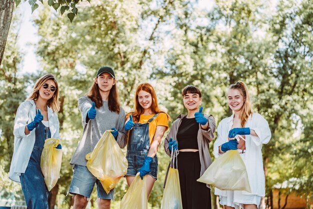 Group of activists friends collecting plastic waste. Guys show thumb up.