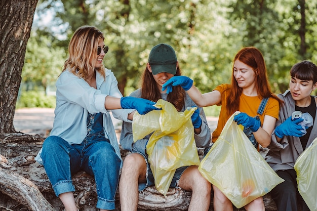 Group of activists friends collecting plastic waste at the park. Environmental conservation.