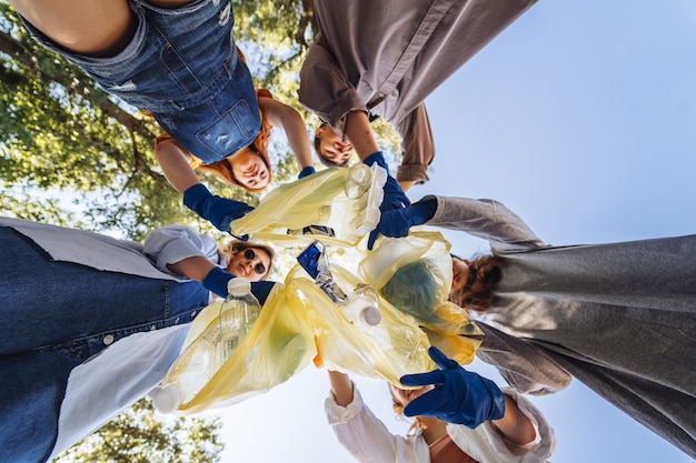 Group of activists friends throw a lot of garbage in a bag. Bottom-up shooting