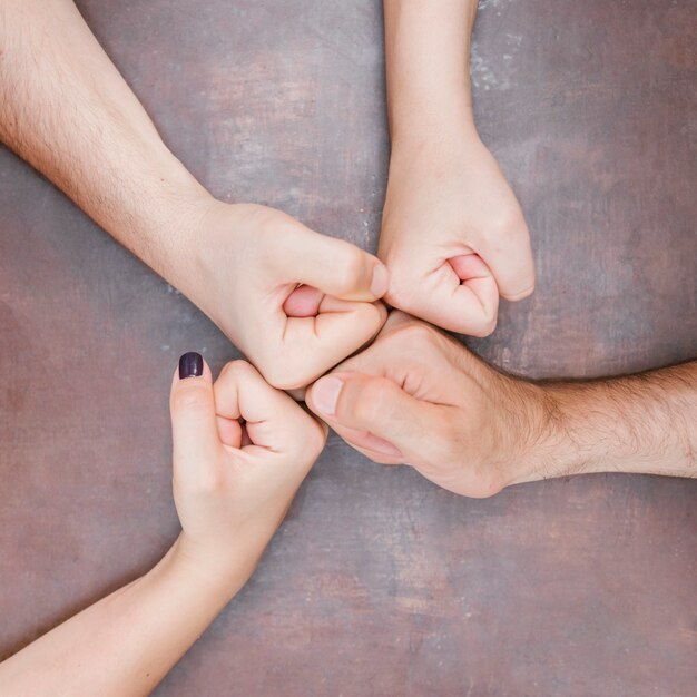 Group of adult friends fist bumping together over table