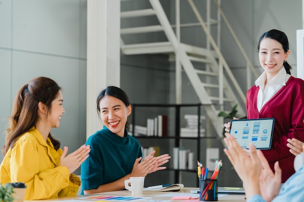 Group of Asia young creative people in smart casual wear discussing business celebrate giving five after dealing feeling happy and signing contract or agreement in office. Coworker teamwork concept.