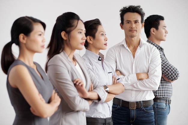 Gruppo di uomini d'affari asiatici in posa in studio con le braccia conserte