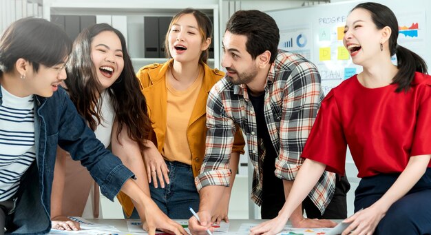 Group of asian and caucasian young creative happy enjoy laugh smile and great success emotion teamwork people business startup entrepreneur casual brainstorm business meeting office background