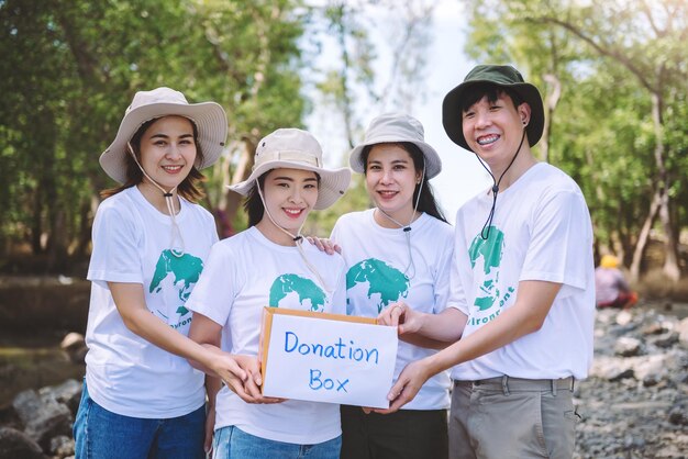 Group of asian diverse people volunteer holding a donation box for fundraiser to emergency situation such as help ukraine flood victims food for children charity eventVolunteering conceptual
