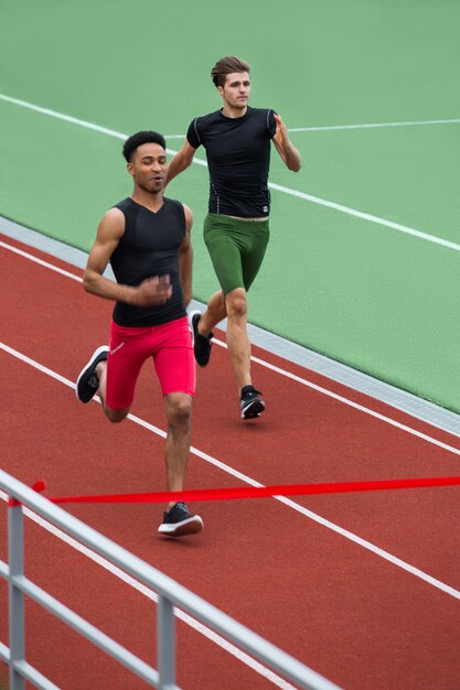 Группа мужчин спортсмена бегут на беговой дорожке на открытом воздухе