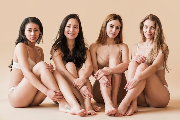 Group of attractive young women in underwear sitting in studio