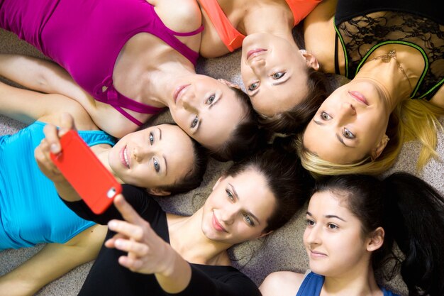 Group of beautiful sporty girlfriends taking selfie, self-portrait with smartphone view from top