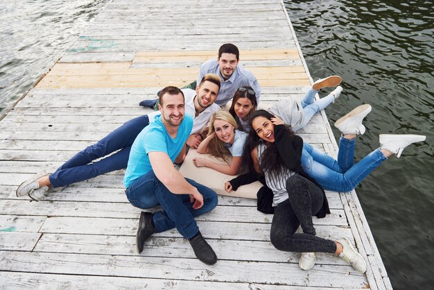 Group of beautiful young people on the pier, friends satisfaction creates emotional life.