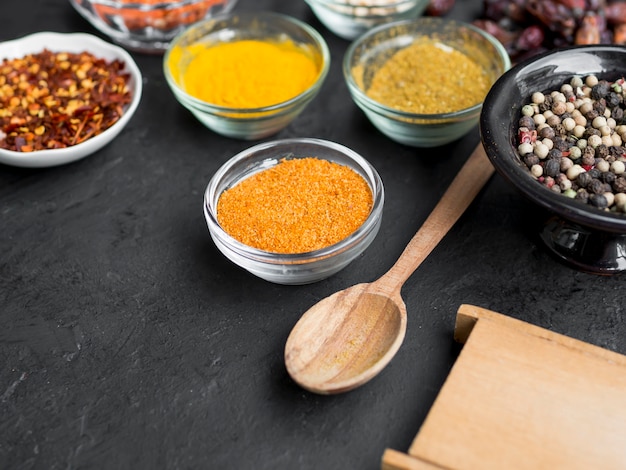 Group of bowls full of spices on black background