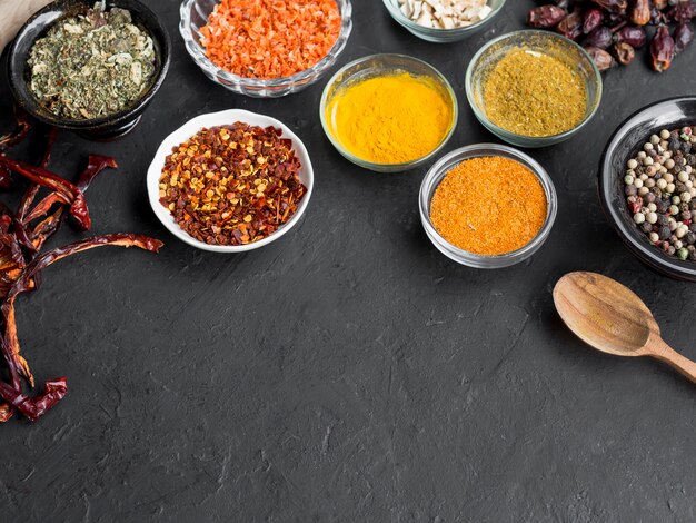 Group of bowls full of spices on black background