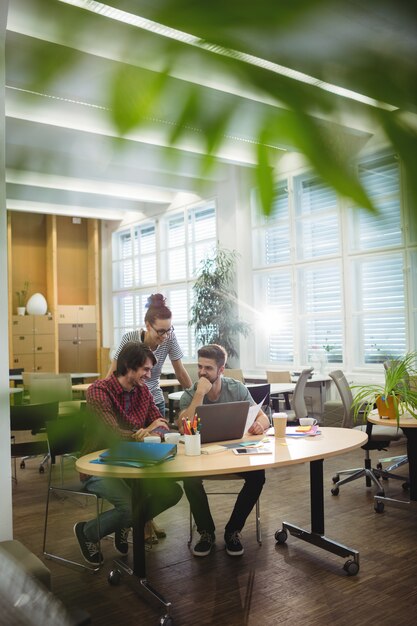 Group of business executives discussing over laptop at their des