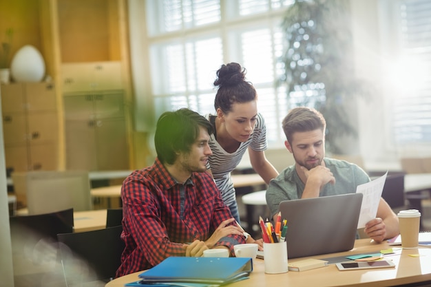 Group of business executives discussing over laptop at their des