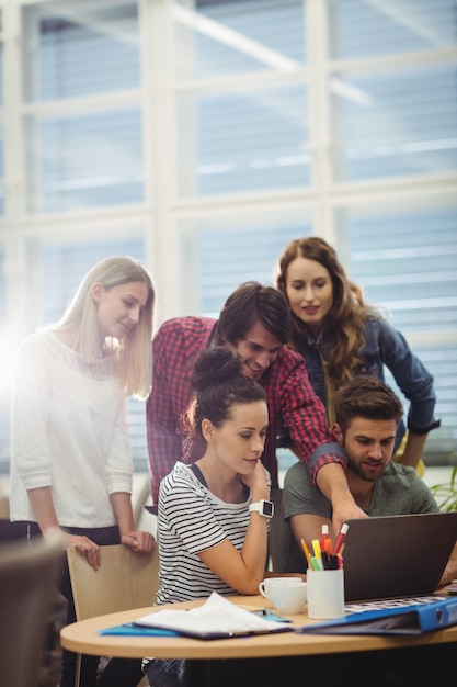 Group of business executives discussing over laptop at their des