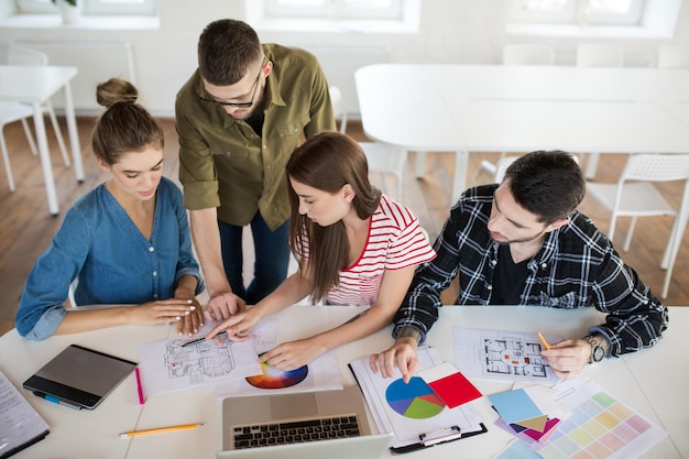 Foto gratuita gruppo di uomini e donne d'affari che lavorano con schizzi e laptop mentre trascorrono del tempo al lavoro giovani creativi che discutono premurosamente di lavorare insieme in un ufficio moderno