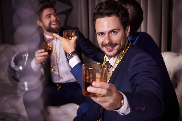 Free photo group of businessmen with whiskey enjoying at night club