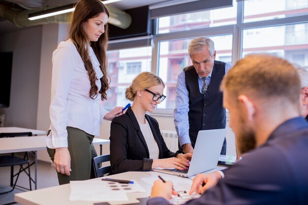 Group of businesspeople looking at laptop in the meeting