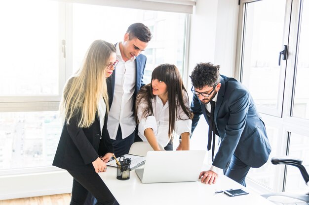 Group of businesspeople standing in the office looking at laptop in the office