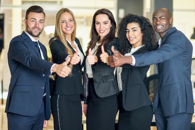 Foto gratuita gruppo di imprenditori con il pollice gesto in ufficio moderno. persone multietniche che lavorano insieme. concetto di lavoro di squadra.