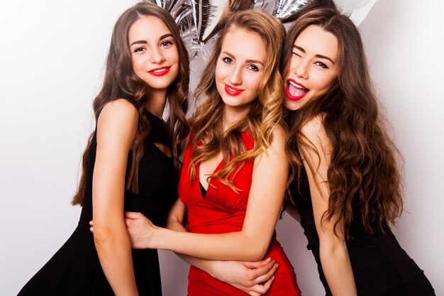 group of celebrating  friends posing in studio. Three pretty woman have fun, winking  ,laughing  and looking at camera.