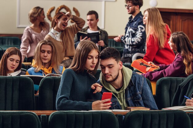 レッスン前に講堂に座っている陽気な幸せな学生のグループ