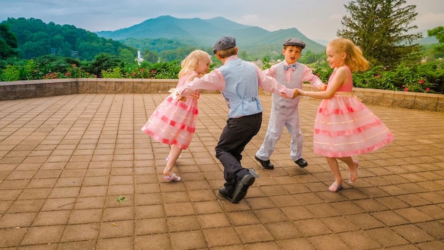 美しい緑に囲まれたエリアで一緒に遊んで踊る陽気な子供たちのグループ