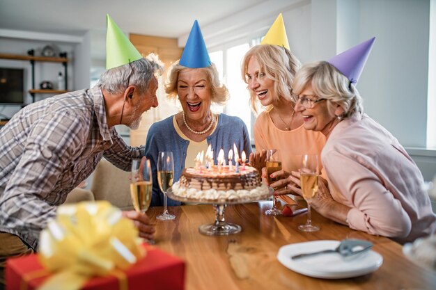 Group of cheerful seniors having fun while celebrating friends birthday at home