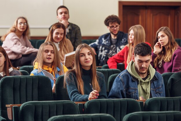 Группа веселых студентов сидит в аудитории перед уроком.