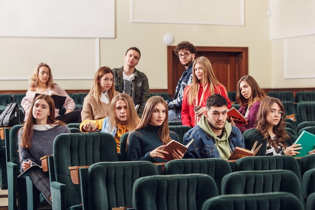 Il gruppo di allegri studenti seduti in un'aula prima della lezione.