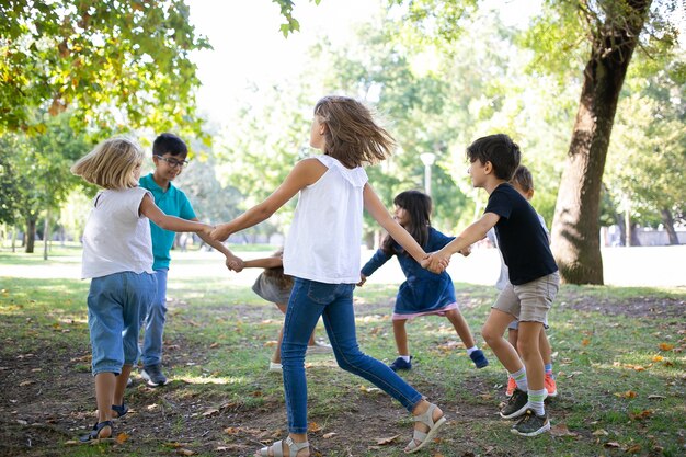 手をつないで踊り、野外活動を楽しんだり、公園で楽しんだりする子供たちのグループ。キッズパーティーや友情の概念