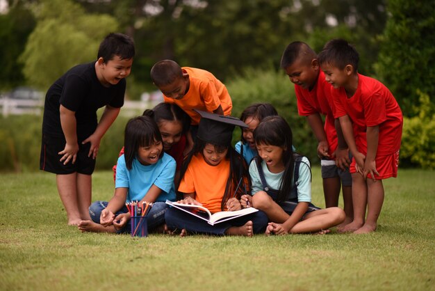 Gruppo di bambini che si trovano leggendo sul campo di erba