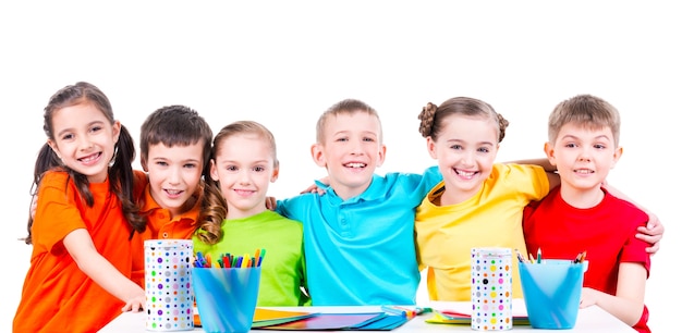 Foto gratuita gruppo di bambini seduti a un tavolo con pennarelli, pastelli e cartoncini colorati