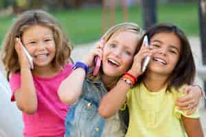 Foto gratuita gruppo di bambini che usano i telefoni mobili nel parco.