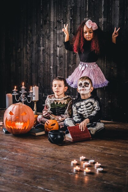 Group of cute multiracial kids in scary costumes during Halloween party in an old house. Halloween concept.