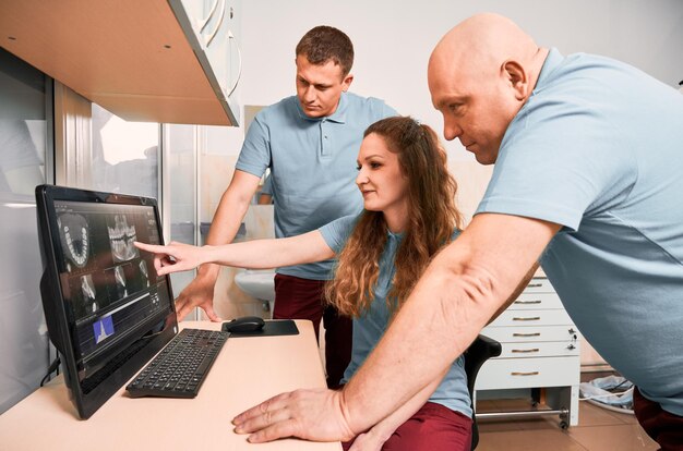 Group of dentists analyzing scan of patient teeth