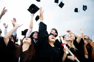 Free photo group of diverse grads throwing caps up in the sky